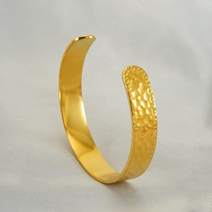Detailed view of golden stainless steel open cuff bracelet with hammered texture finish