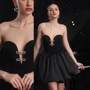Detail of elegant black tube dress featuring sparkling rhinestone bow buckles on the neckline