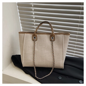 Detail of canvas bucket tote with brown leather trim and metal eyelet on black blazer