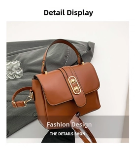 Detail shot of a brown textured leather crossbody bag with a gold oval clasp and top handle