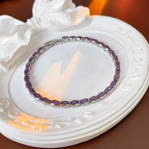 Close-up of geometric purple zircon bracelet with silver metal chain on white plate