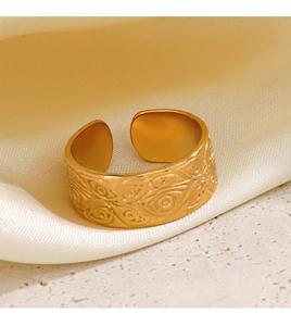 Detail view of a vintage gold-plated wide open ring with embossed patterns on silk fabric