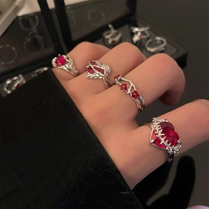 Elegant silver rings with red gemstones featuring heart and branch designs on a hand