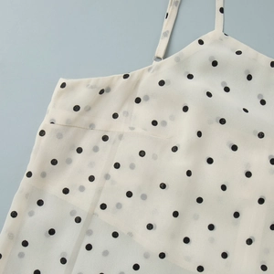 Close-up of white polka dot camisole with thin straps and metallic ring hardware