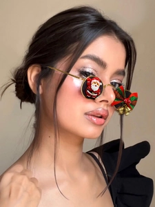 Detail of Christmas Y2K sunglasses with gold frames and Santa Claus doll with red green bow