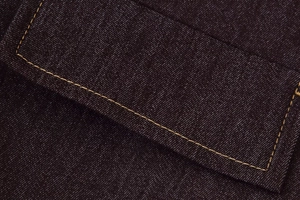 Gros plan des surpiqûres jaunes contrastées sur la poche d'une veste en denim foncé