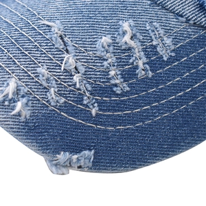 Macro shot of distressed blue denim fabric with vintage frayed holes and white stitching