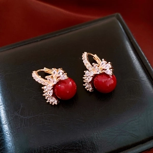 Detailed close-up of 18k gold plated red pearl earrings with sparkling white zircons