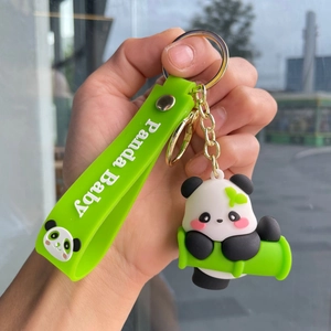 Detail of cute panda plush keychain on green bamboo with a branded silicone wrist strap