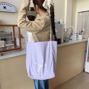 Detail of purple canvas tote bag with Bonjour magic print and green checkered strap