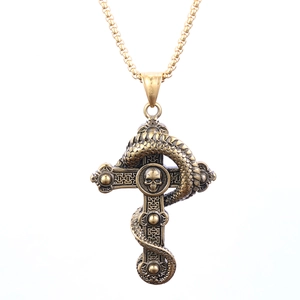 Close-up of a vintage gothic cross pendant with a serpent and skull in antiqued gold finish