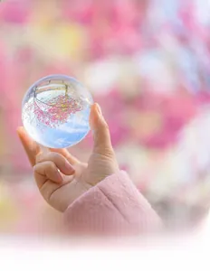 Close-up of a hand holding a high-clarity crystal ball with beautiful light refraction