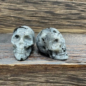 Macro detail of 2.8cm hand-carved natural stone crystal skull ornaments on wooden shelf