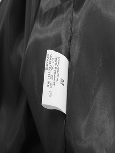 Détail de l'étiquette de lavage montrant la taille M et le tissu 100% polyester