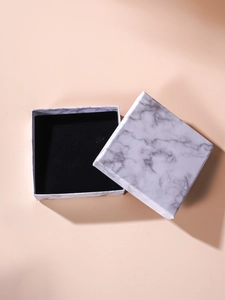 Detail view of square marble texture jewelry box with plush black velvet interior lining