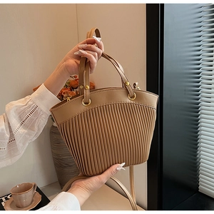 Close-up of pleated khaki tote bag with gold metal rings in a lifestyle setting