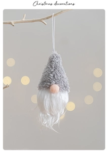 Plush Christmas gnome hanging ornaments in grey and pink on a festive branch with bokeh