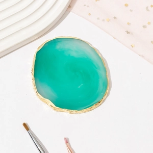 Detailed view of teal resin agate palette with gold electroplated edge on elegant fabric