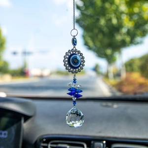 Evil eye suncatcher with blue crystal beads and a prism ball hanging in a car