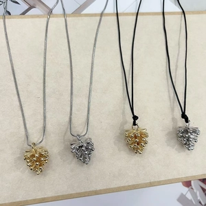 Detailed view of pine cone pendants in gold and silver finishes with various chains