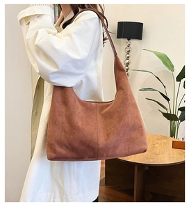 Macro detail of large capacity deep brown suede hobo bag styled with a white trench coat