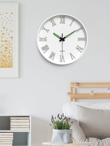 Detail of minimalist quartz wall clock showing black Roman numerals and luminous green hands