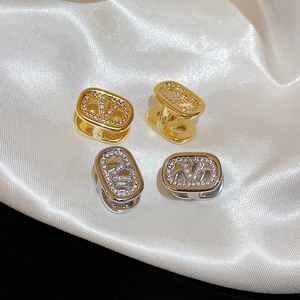 Macro detail of oval hoop earrings with V-shaped logo and pave-set cubic zirconia crystals