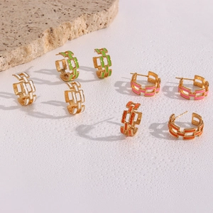 Macro shot of geometric chain earrings in green, white, pink, and orange enamel
