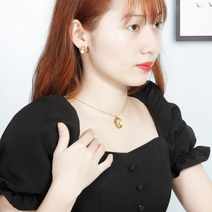 Gros plan d'un collier en acier doré et boucles d'oreilles perles sur mannequin
