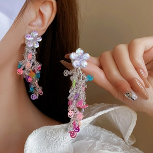 Gros plan de boucles d'oreilles fleurs en tissu avec paillettes smiley et glands perlés