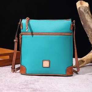 Close-up of turquoise pebbled leather crossbody bag with brown trim and metal logo plate