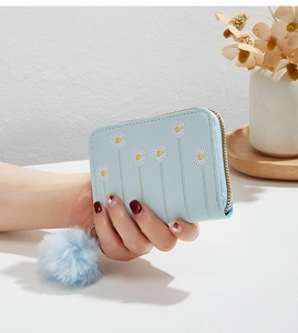 Detail of light blue floral embroidered mini purse with soft pompom zipper charm