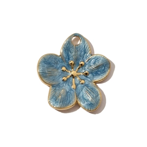 Detail of blue enamel flower pendant with gold edges and pearl texture on white background