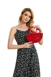 Detail of red semicircular bamboo handbag with hollowed handles and sunburst design