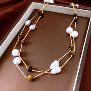 Détail du collier double couche en œil de tigre et perles baroques sur velours
