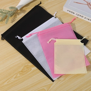 Non-woven drawstring storage bags in four colors on a wooden table with home decor
