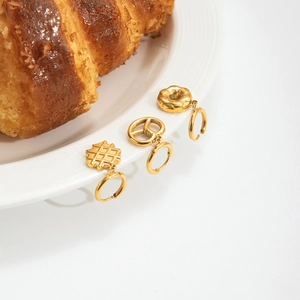 Gold stainless steel hoop earrings set with waffle and pretzel charms on white plate