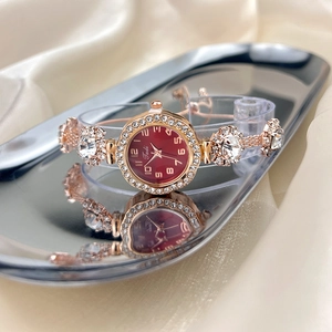 Detail view of rose gold quartz watch with red dial and crystal bezel on silk background
