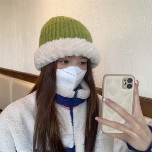 Detailed texture of green ribbed knit hat with white faux shearling brim for winter