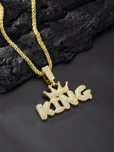 Detail of gold-plated KING crown pendant with micro-pave crystals on a charcoal base