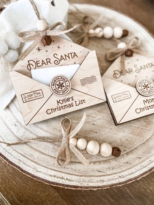 Detail of wooden Christmas envelope ornament with rustic twine, bead, and vintage bell
