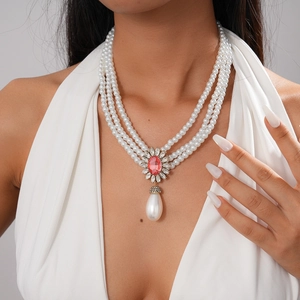 Detail of a multilayer baroque pearl necklace featuring a pink gemstone and drop pendant