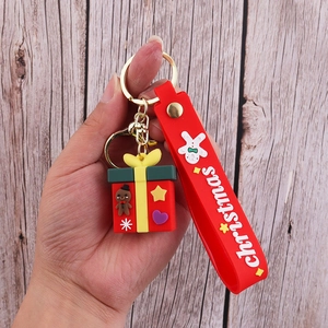 Close-up of a Christmas gift box keychain with a red silicone wristlet and gold metal clasp