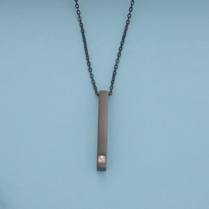 Makroaufnahme eines schwarzen rechteckigen Anhängers mit rosa Edelstein an schwarzer Kette