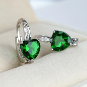 Detail shot of heart-shaped emerald green earrings with pave zircons in a jewelry box