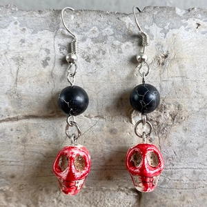 Detail of gothic Halloween earrings featuring black beads and red bloody skull pendants