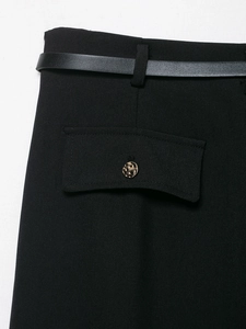 Dettaglio del blazer nero con tasche a fibbia metallica e sottile cintura abbinata