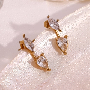Detail view of 18K gold plated teardrop zirconia stud earrings on a water-beaded shell