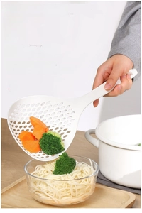 Detail of large white slotted spoon draining vegetables from a white enamel pot