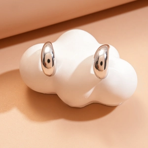 Macro view of teardrop double-layered silver stud earrings with a polished mirror finish